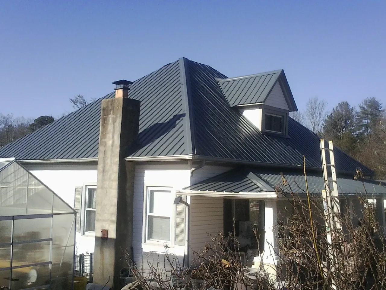 Dark blue standing seam metal roof on a white farmhouse with dormer — Slate & Tile Roof Repair by Roofing Brothers in Mohnton