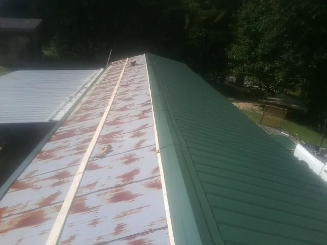 Old rusted panels beside newly installed green metal roofing — Wind Damage Roof Repair by Roofing Brothers in Mohnton