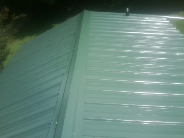 New green metal panels meeting at the ridge of a roof — Flat Roof Repair work by our crew in Mohnton
