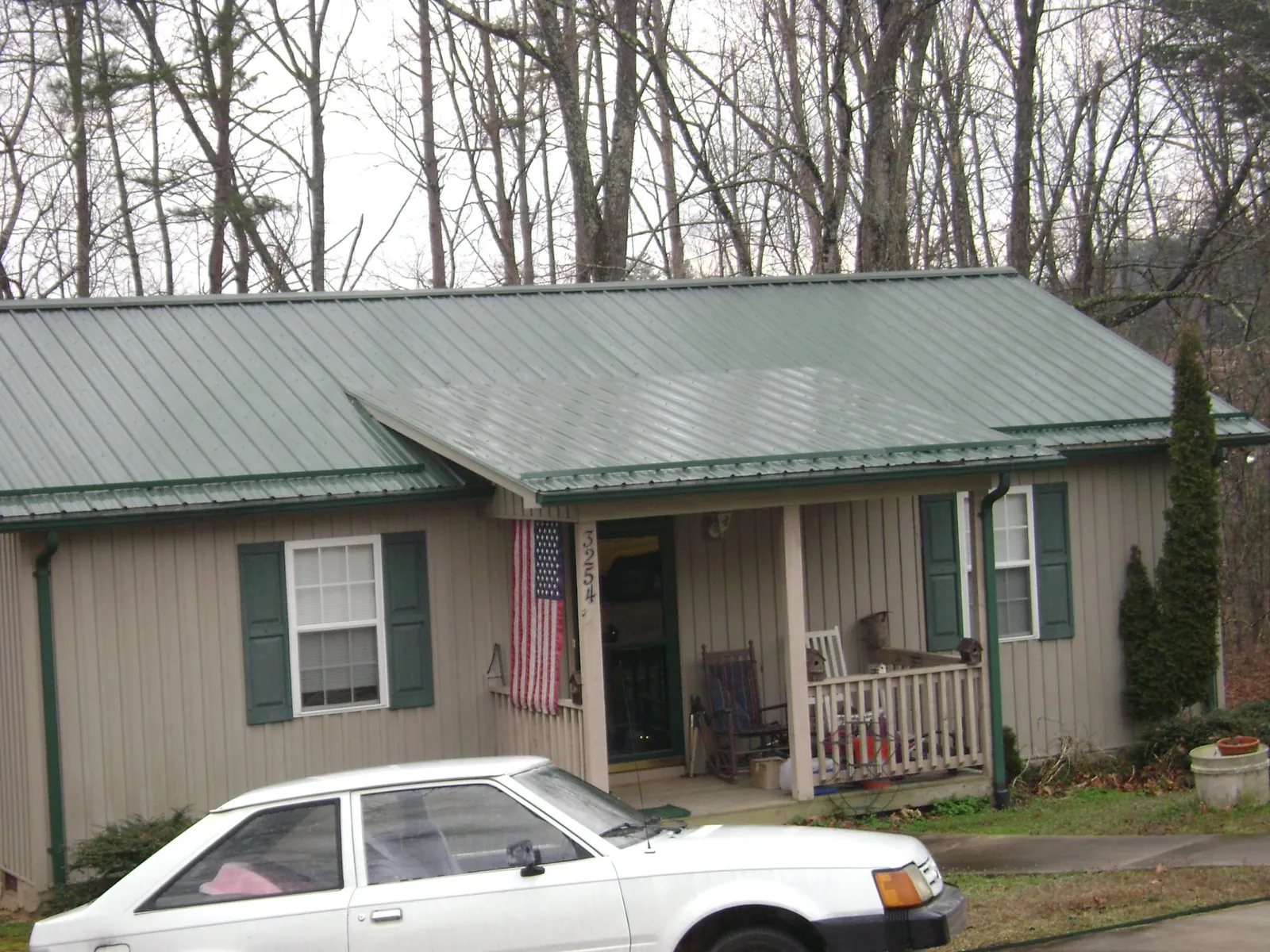 Green metal roof and front porch on a tan sided cottage in Mohnton