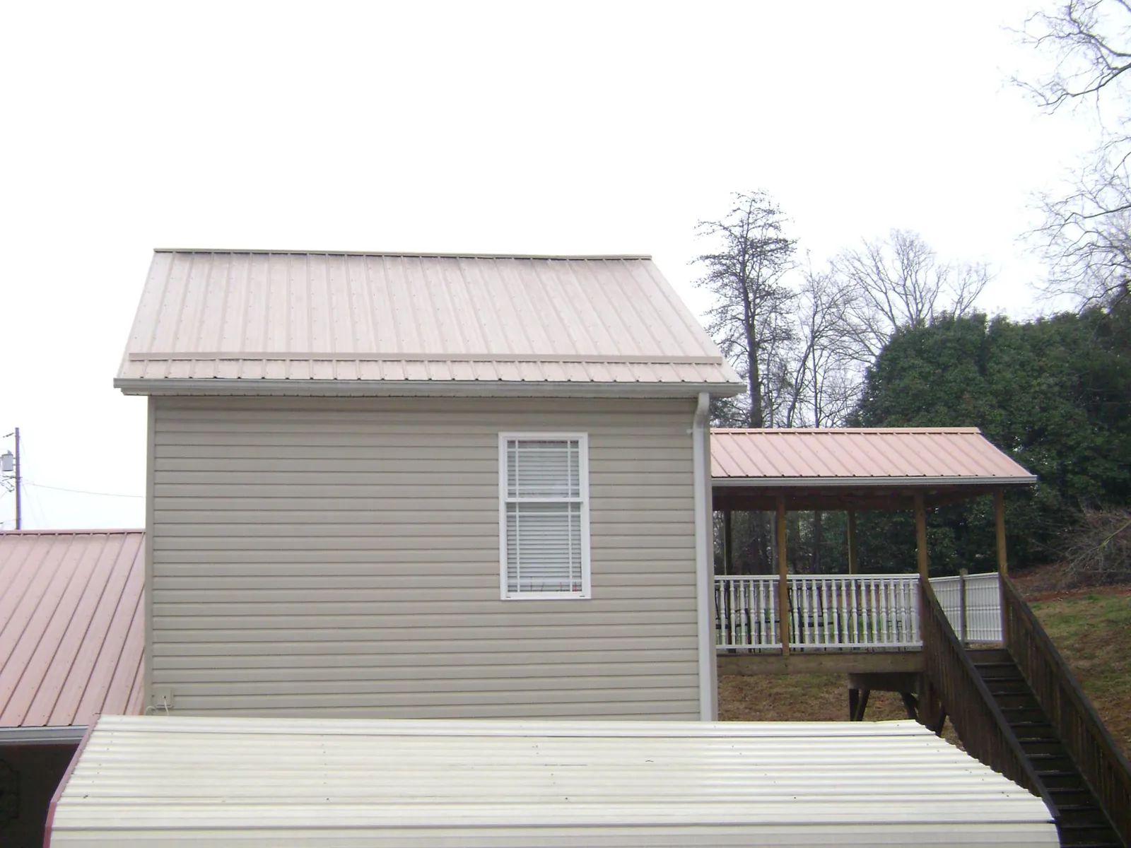 Tan metal roofs on a two story addition and attached porch, from a Roof Replacement job in Mohnton