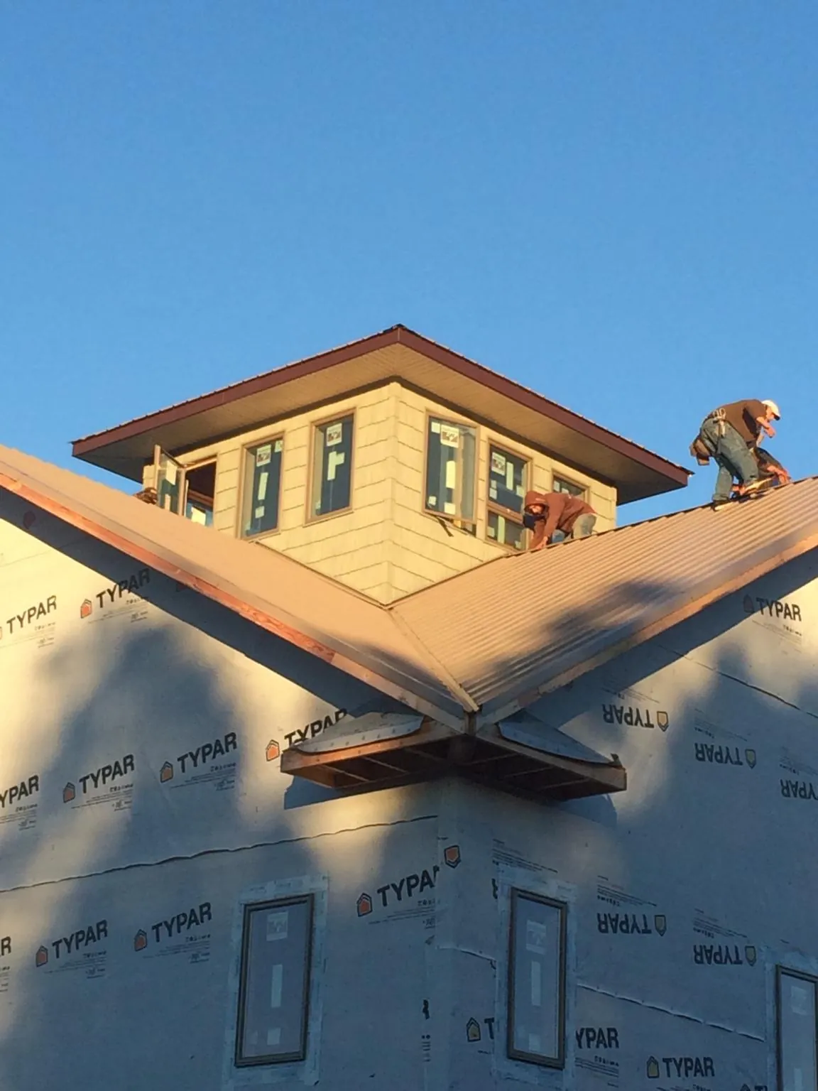 Roofers working around a rooftop cupola on a new metal roof at sunset — Roof Waterproofing in Mohnton by Roofing Brothers